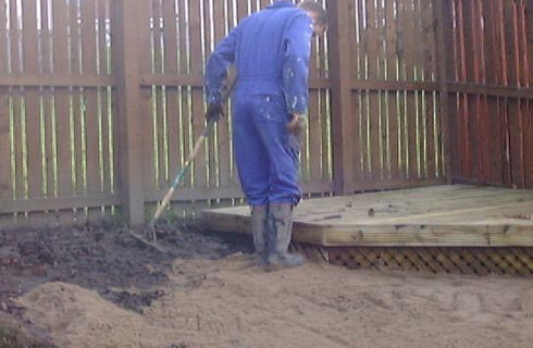 person laying sand in preparation for turf