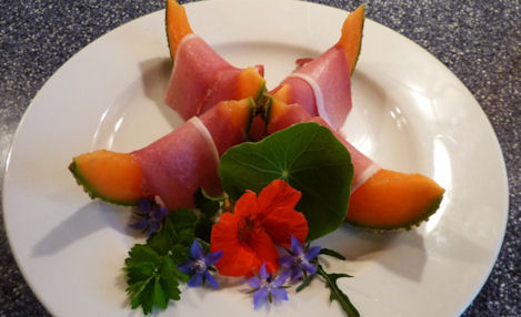 nasturtium flower on a plate with melon and ham
